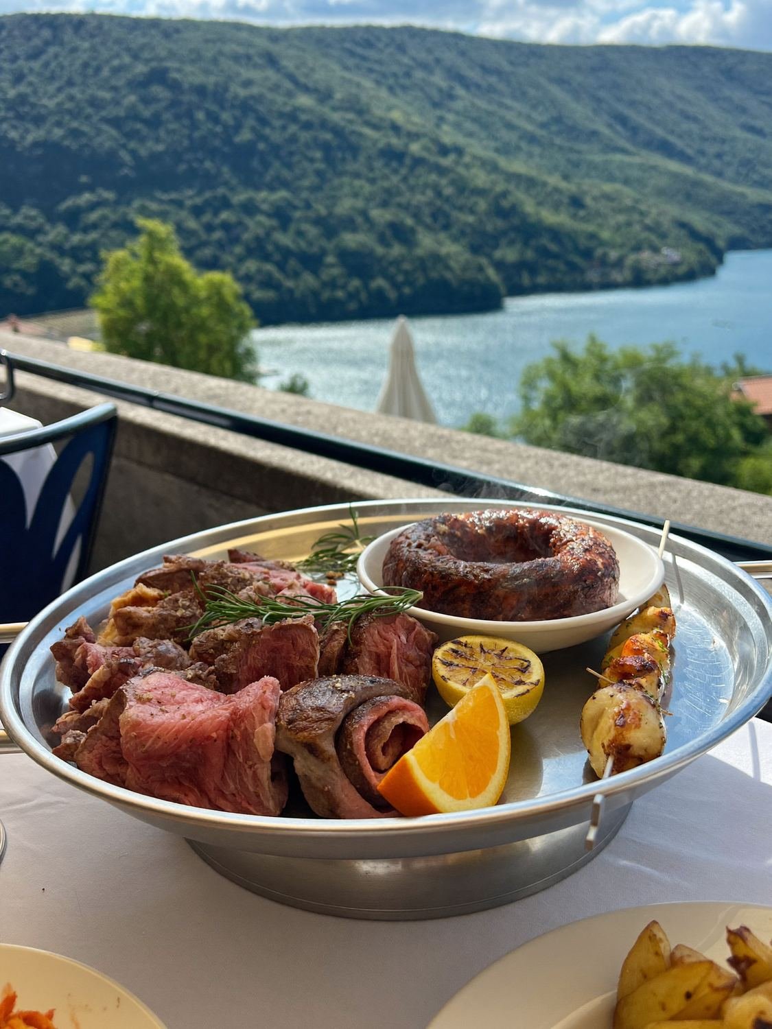 Grigliata mista di carne servita su vassoio con vista lago